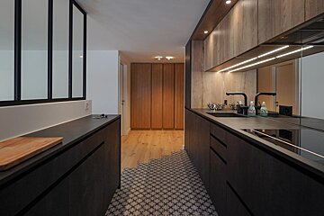 A kitchen with black cabinets and wooden cabinets