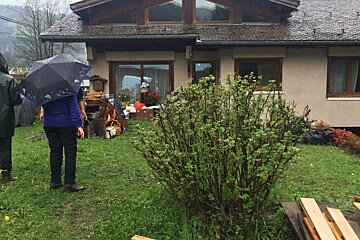 people in ran macs with umbrellas in a garden in morzine
