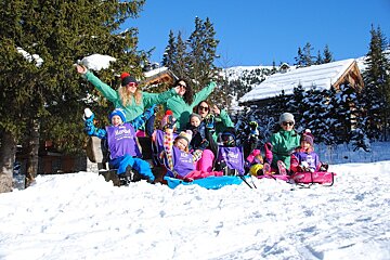 A group of children are playing in the snow and one of the children is wearing a purple jacket that says mermaid