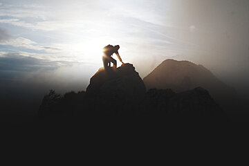 A silhouette of a person standing on top of a mountain