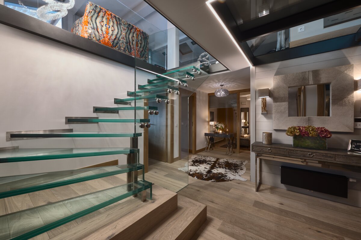 A glass staircase leads to the second floor of a house