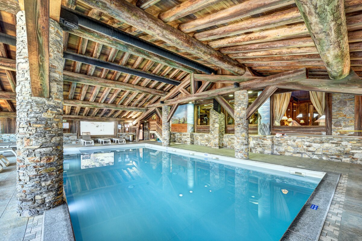 A large indoor swimming pool surrounded by stone and wood