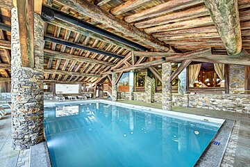 A large indoor swimming pool surrounded by stone and wood