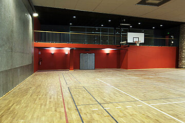 An empty gym with a basketball hoop in the middle