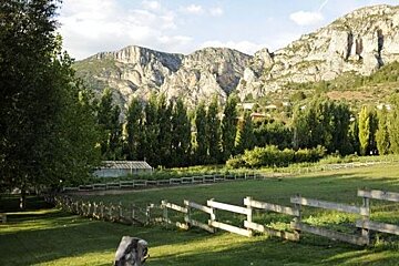 Field with wood fence and rocky mountains in the background