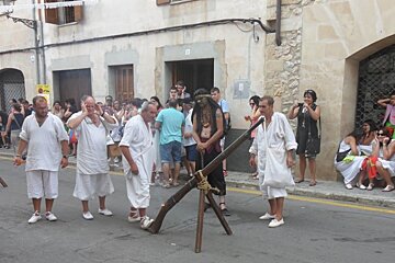 A group of men in white clothes with a gun in the street