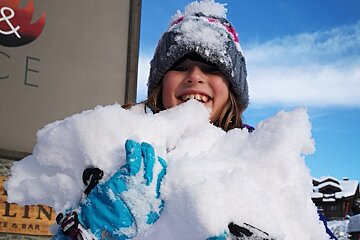 A girl is holding a pile of snow in front of a sign that says gelin