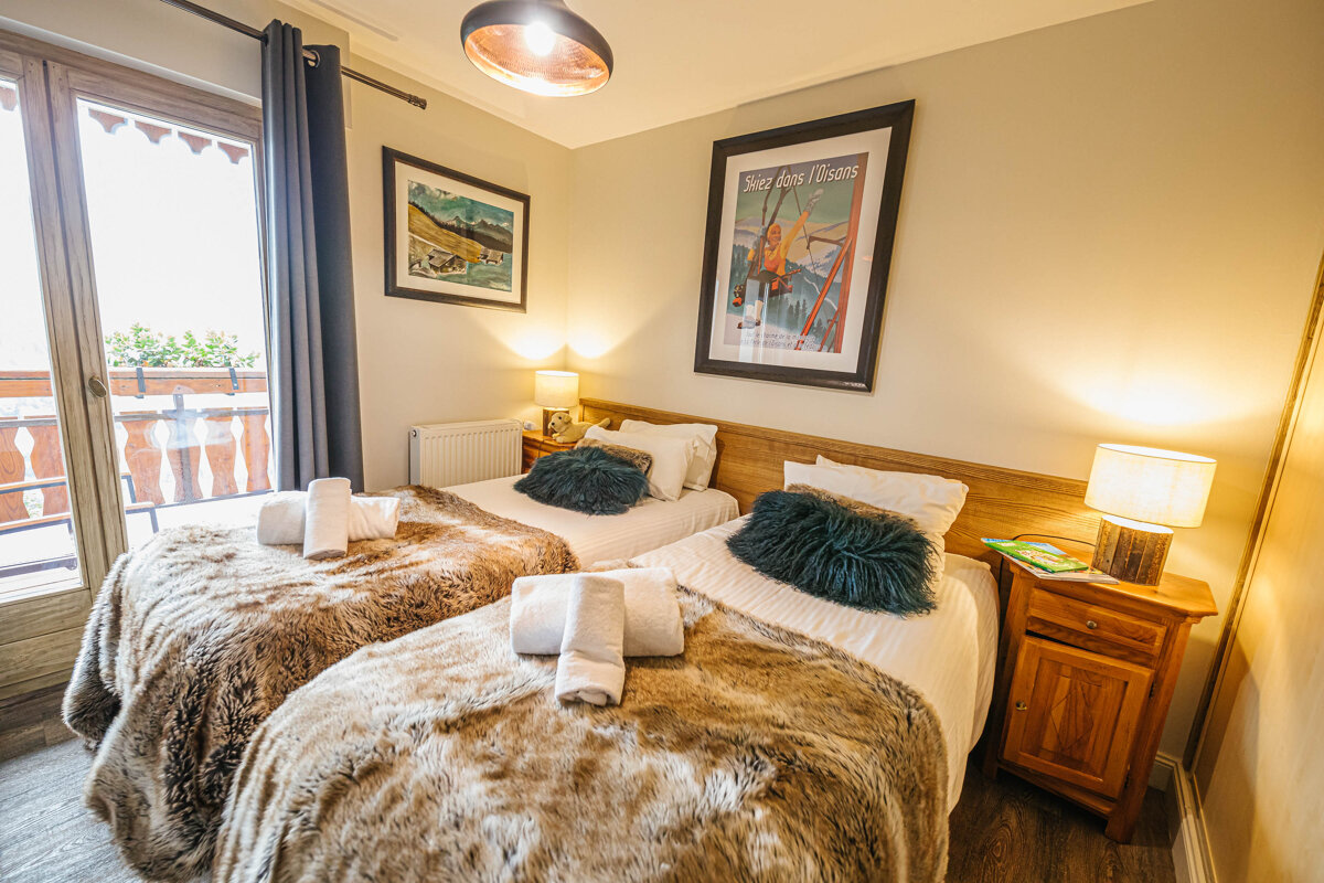 A bedroom with two beds and a framed picture of a ski lift on the wall