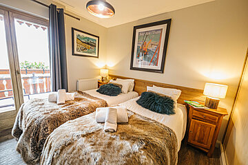 A bedroom with two beds and a framed picture of a ski lift on the wall