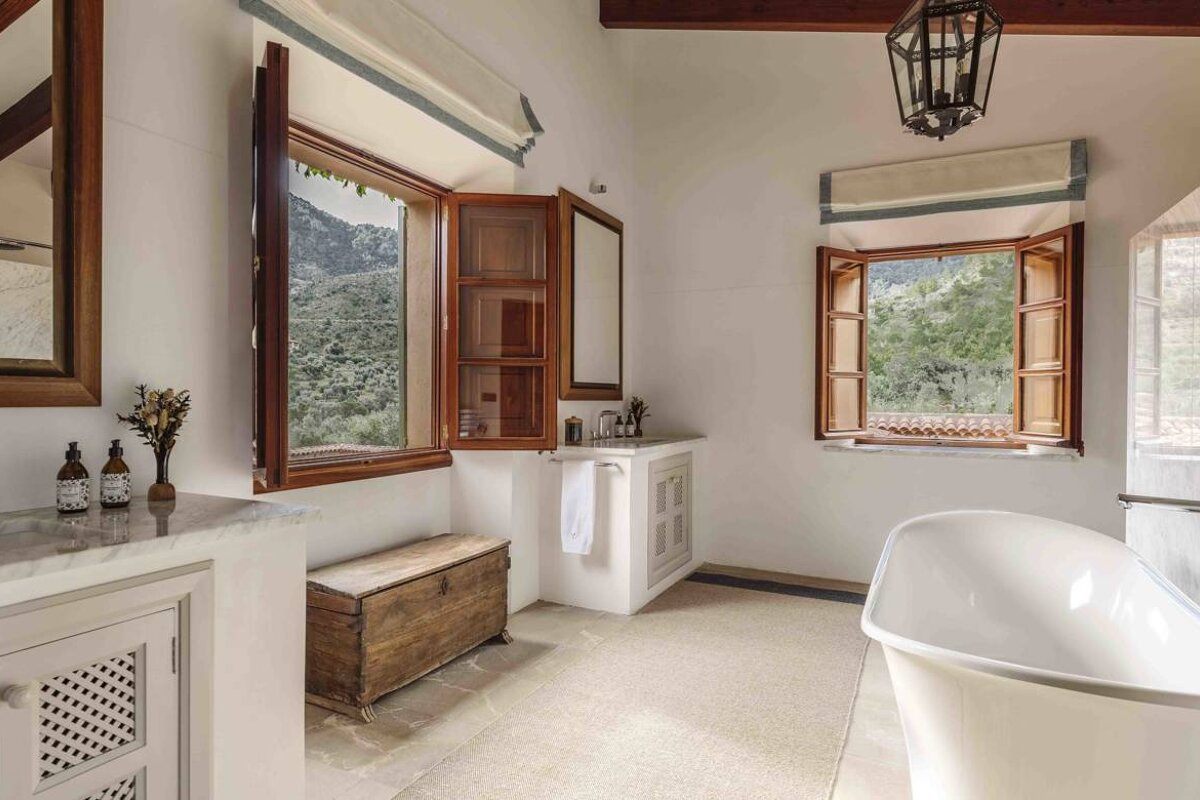 A bathroom with a tub a sink and two windows