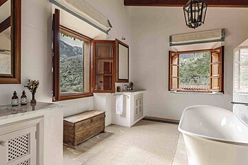 A bathroom with a tub a sink and two windows