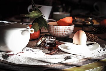 A jar of honey sits on a table next to an egg