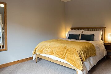 A bedroom with a bed and a mirror on the wall