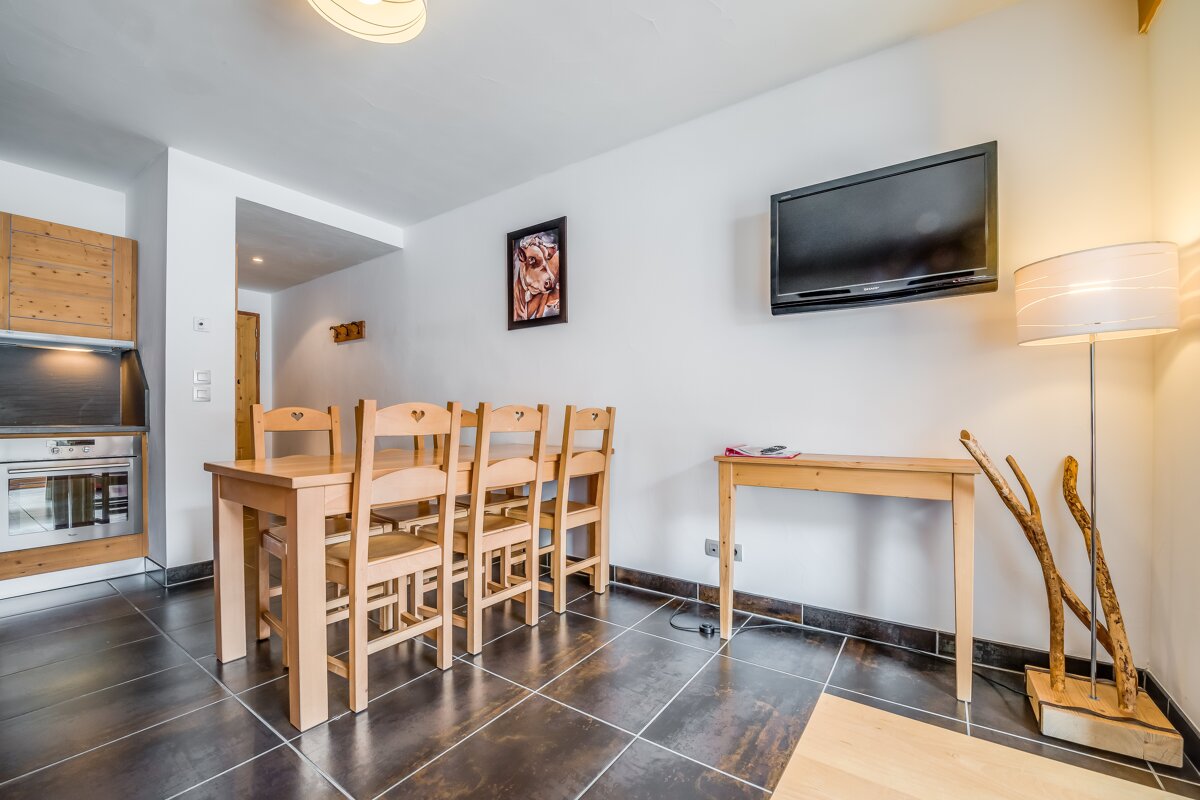 A dining room with a table and chairs and a flat screen tv