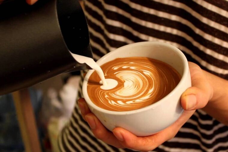 a woman pouring milk into a coffee