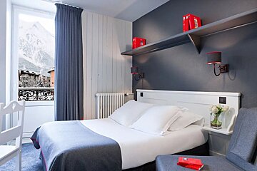 A hotel room with a bed and a chair