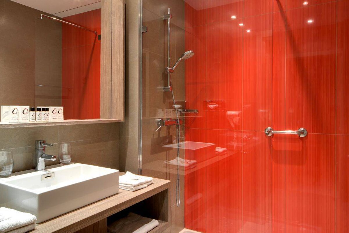 A bathroom with a sink and a red wall