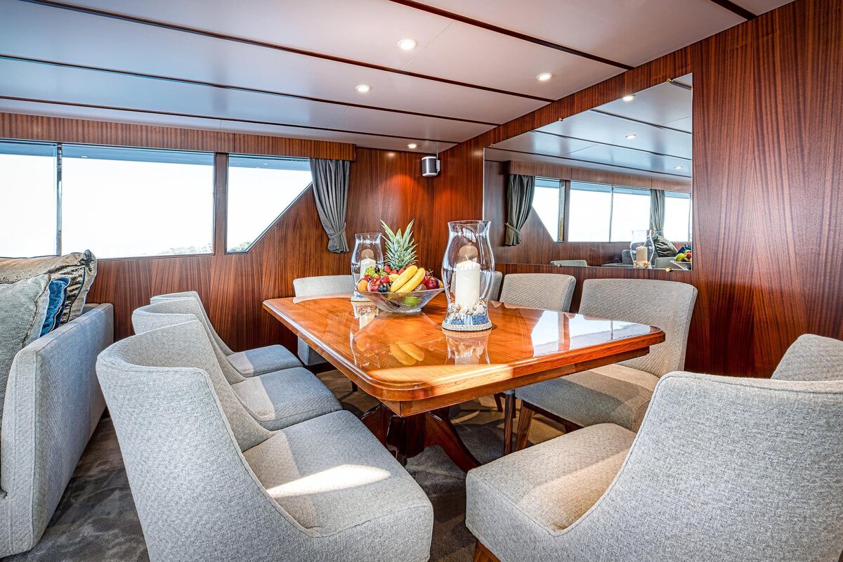 A dining room table with a vase of fruit on it