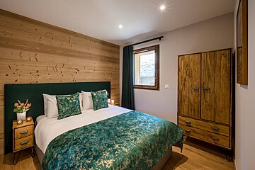 A bedroom with a bed and a wooden cabinet