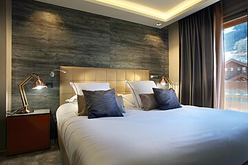 A hotel room with a bed and two lamps