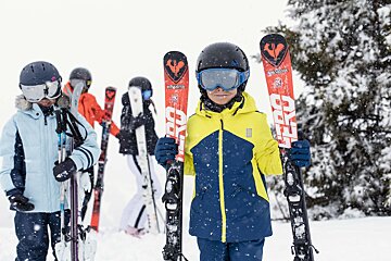 A boy holding a pair of rossignol skis
