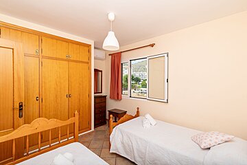 A bedroom with two beds a dresser and a window