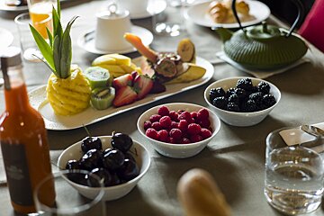 A table with bowls of fruit and a bottle of orange juice