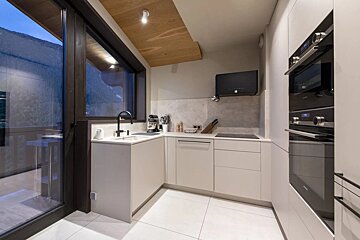 A kitchen with white cabinets and black appliances including a siemens oven