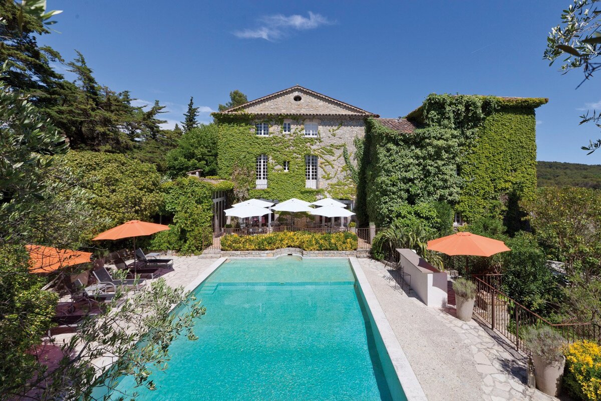 A large house with a swimming pool in front of it
