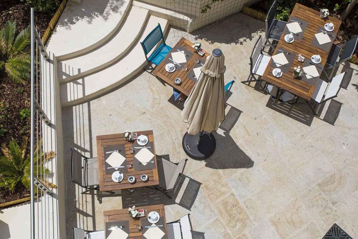 An aerial view of a patio with tables and chairs and an umbrella