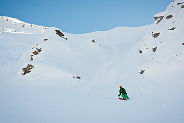 a skier in green outfit off piste