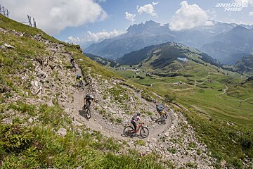 A group of people riding bikes on a trail with a mountain in the background