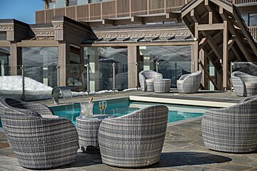 A table with two glasses of champagne sits in front of a swimming pool