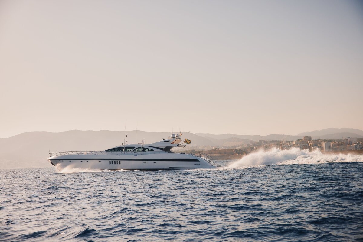 A white yacht is floating in the ocean with mountains in the background