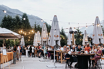 A group of people are sitting at tables under umbrellas that say red bull