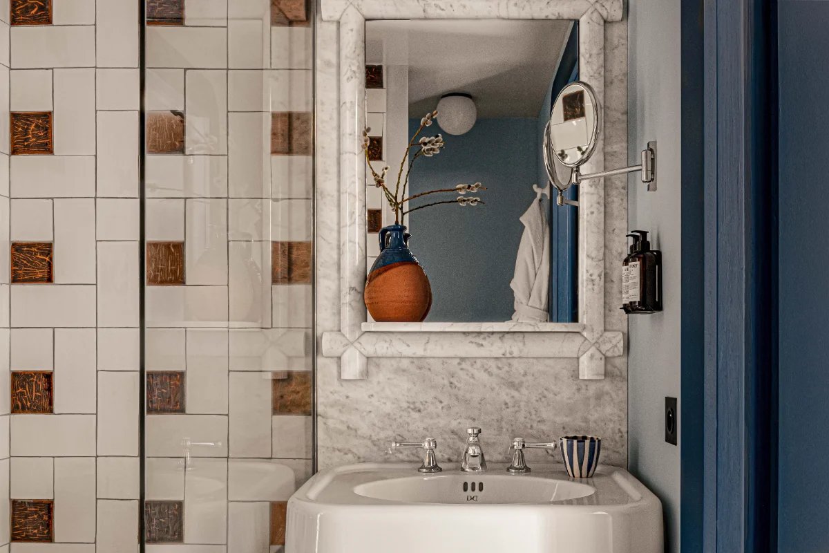 A bathroom with a sink a mirror and a vase
