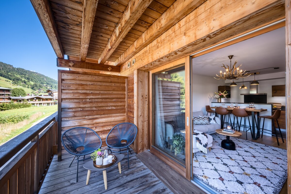 A balcony with two chairs and a table in front of a sliding glass door
