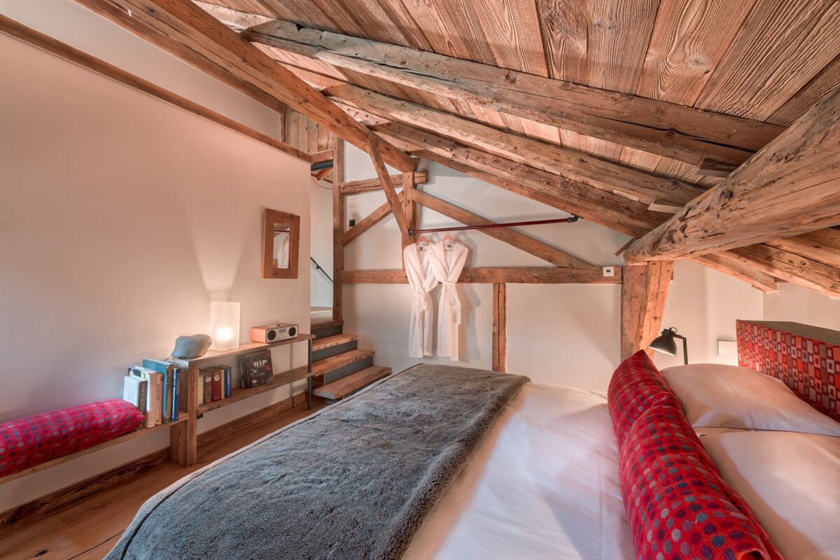 A bedroom with wooden beams and a bed