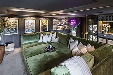 A living room with a green couch and a neon sign that says all has what she 's carry