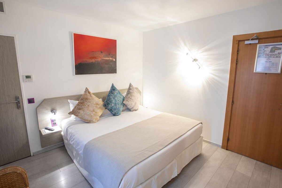 A hotel room with a bed and a painting on the wall