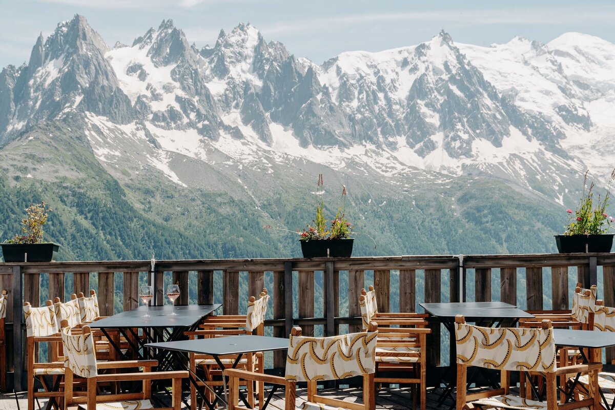 Tables and chairs on a balcony with mountains in the background