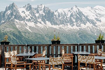 Tables and chairs on a balcony with mountains in the background