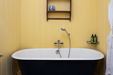 A bathtub in a bathroom with yellow walls