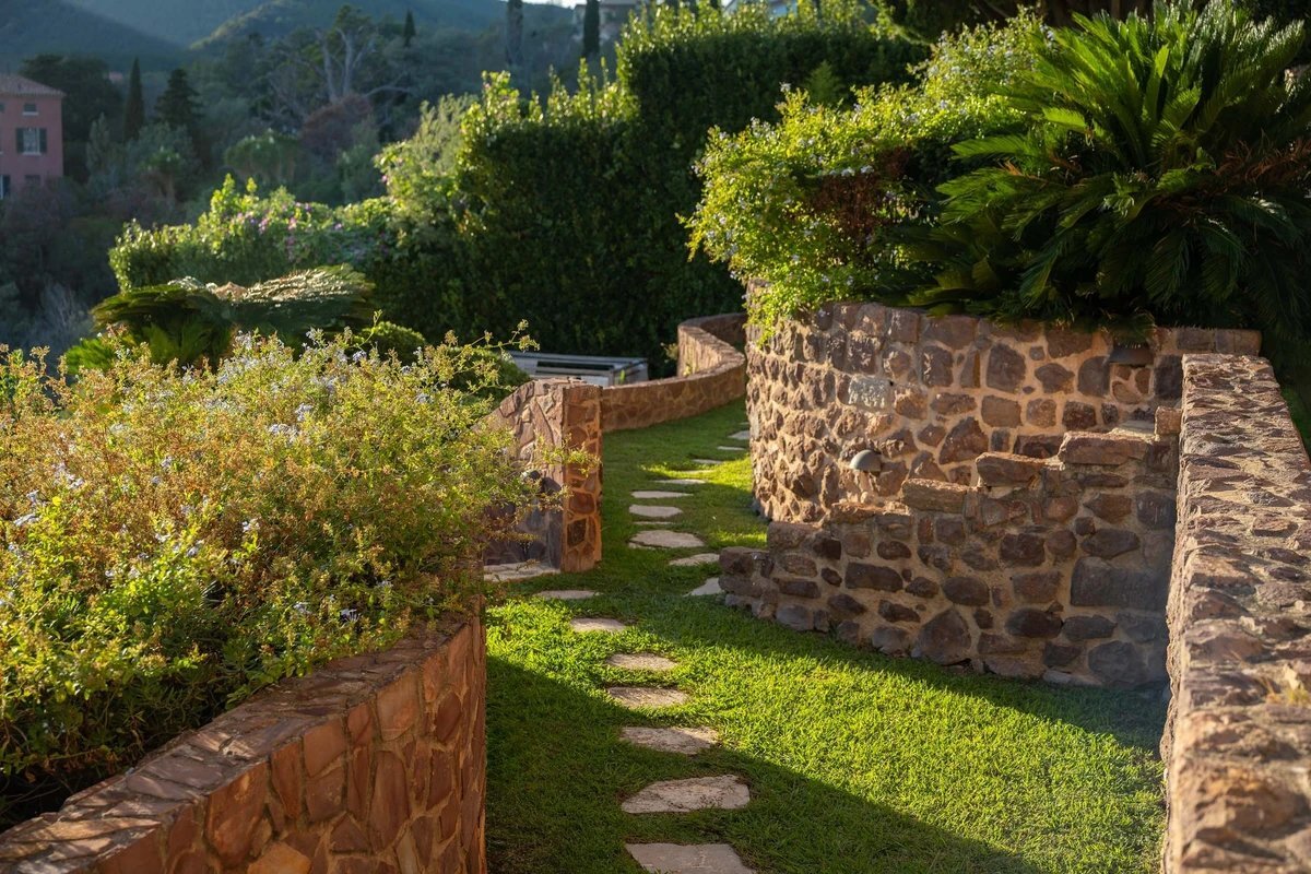 A stone wall surrounds a lush green lawn