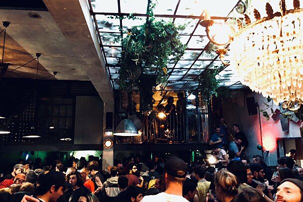 A crowd of people are gathered in a room with a chandelier hanging from the ceiling