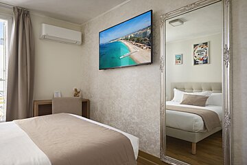 A hotel room with a large mirror and a flat screen tv