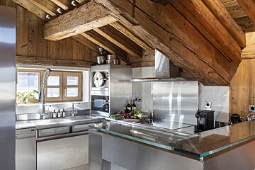 A kitchen with stainless steel appliances and wooden beams