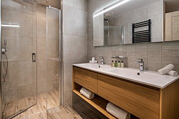 A bathroom with two sinks and a walk in shower