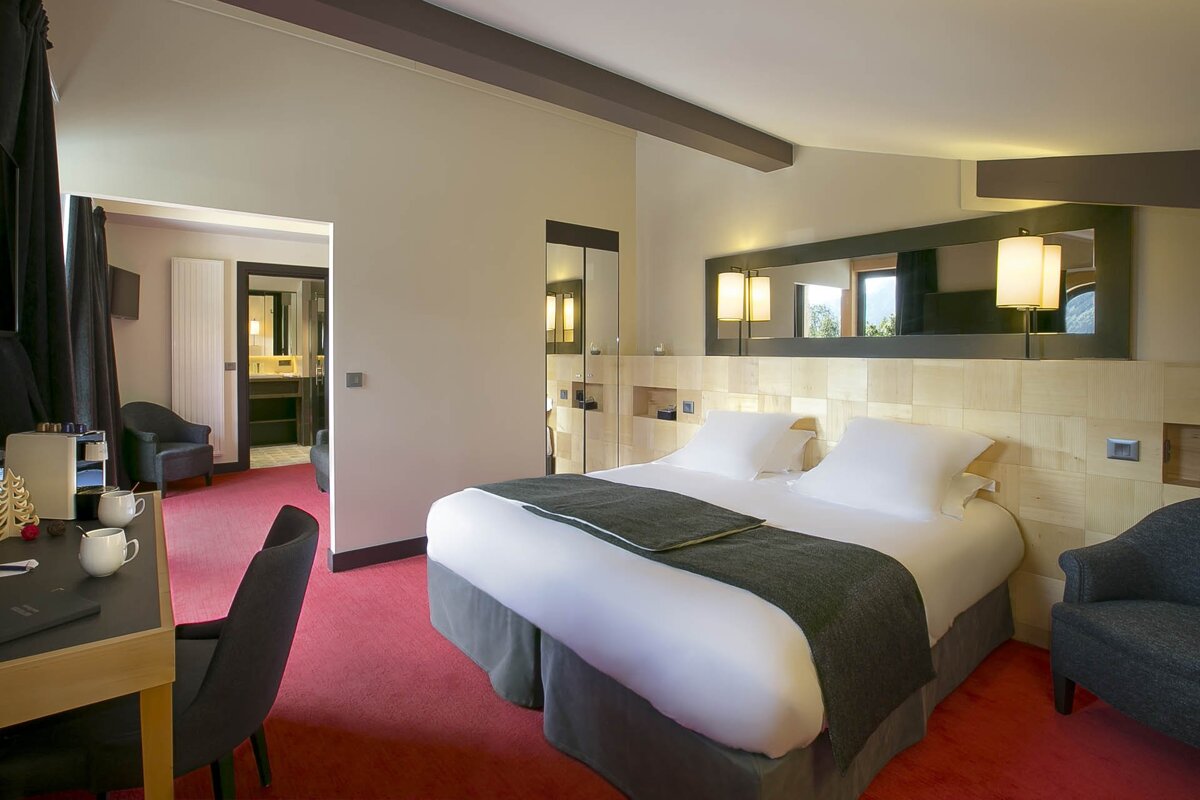 A hotel room with a large bed and a desk