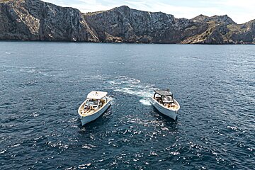 Two boats in the ocean with mountains in the background